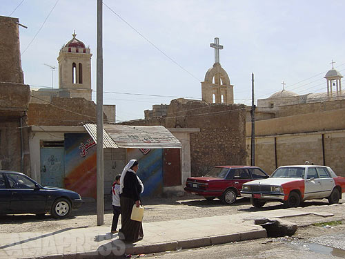 イラク北部、ニナワ県モスル近郊にある小さな町バシカ。十字架のある建物はシリア正教会の建物。街にはイスラム教のモスクや、ヤズディ教の寺院クッブが立ち並ぶ。（写真：玉本英子：２００４年４月）