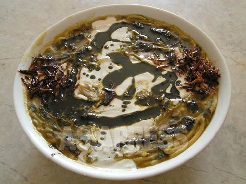 数種のハーブ類と豆、麺を煮込んだアーシュ・レシテ。カリカリに揚げたタマネギとニンニクのスライス、炒めた乾燥ミント、くせのある乳製品キャシュクを上から添えて食べる。