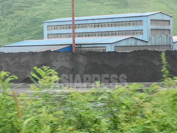 中国側の選鉱場。2005年に建設されたこの工場では、茂山鉱山で採掘された鉄鉱石の鉄含有量を挙げる選鉱作業が行われる。建物の周囲には選鉱を終えた「精鉱」が積まれている。2013年8月、南坪鎮で撮影。