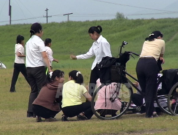 休日の公園でラジカセで音楽を流しながらディスコ風ダンスに興じる若者たち。外部世界の影響を受けているのは明らかだ。ただし公の場でかけられるのは北朝鮮の曲だけ。女性はポニーテールをリボンで括るのが流行っていたようだ。（2006年8月清津市　リ・ジュン撮影）