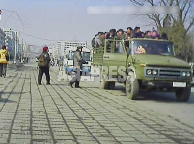 軍用のトラックが金を取って大勢の人を載せている。公共バスが麻痺して、車両を持つ機関や個人が金儲けのチャンスを得た。2013年3月　平安南道平城市でミンドゥルレ撮影