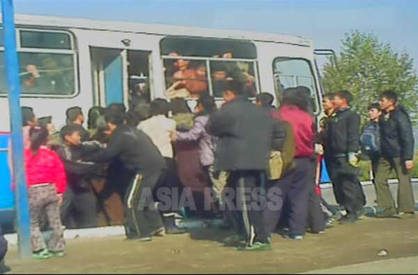 市内バスに乗ろうと殺到する人々。（2012年11月恵山市　リ・フン撮影）】