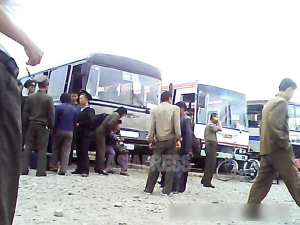 こちらは沙里院市の郊外に位置するバス駐車場。保安員、陸軍、海軍兵士の姿も見える。バスはほとんどが中国の中古車。日本車もちらほら。（2013年9月　リ・フン撮影）】