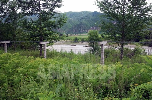 朝中国境の川・豆満江沿いでは、鉄条網の増設が続いている。写真は吉林省の龍井市三合鎮に張られた鉄条網。対岸は北朝鮮の会寧市。2012年7月30日　パク・ヨンミン撮影（アジアプレス）