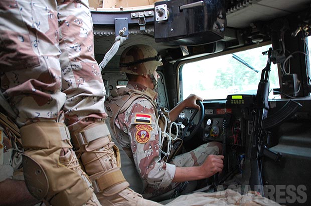 イラク軍車両に乗り込む。米国製ハンヴィーは防弾防爆装甲強化タイプだが、それでも武装組織の路肩爆弾で吹き飛ばされる被害があいついでいた。左は機銃兵の足。ルーフ部分で機銃を構え警戒する。（2010年・モスル：撮影・玉本英子）
