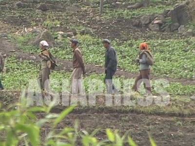 種まき前の草刈り作業に出てきた農民たち。山の斜面の狭い土地も利用する姿は痛々しい。（2005年4月　中国側から石丸次郎撮影）