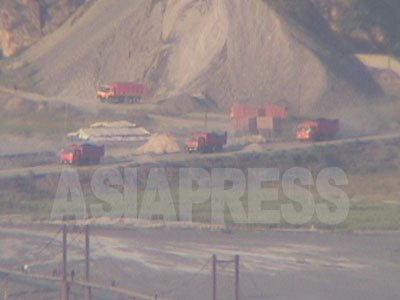 茂山鉱山で採掘した精鉱を積載した中国の40トンダンプの隊列。2008月7月時点で、一日あたり約6000トンが中国に搬出されている。（2005年8月中国側から石丸次郎撮影）