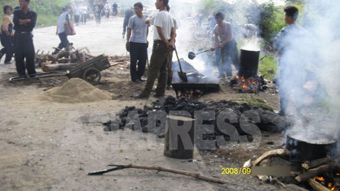 道路舗装のためアスファルトを熱している珍しい写真。薪を燃料にしている。北朝鮮では、都市間の幹線以外、大半の道路が未舗装のままである。