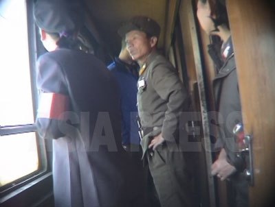 列車の中。制服姿の軍人は警務官、後姿が女性乗務員。警務官は、軍人の犯罪や不良行為に目を光らせる。（2005年5月　リ・ジュン撮影）