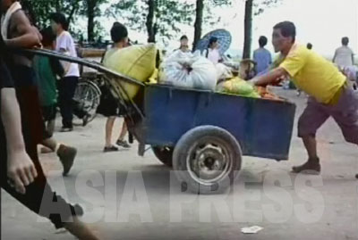 荷物運びや自転車修理、軽食販売など、市場での活動で現金を得ている人々にとっては、市場が混乱することは生活への打撃に直結する。写真は黄海北道沙里院（サリウォン）市の市場で荷役をする人。（2007年8月　リ・ジュン撮影）