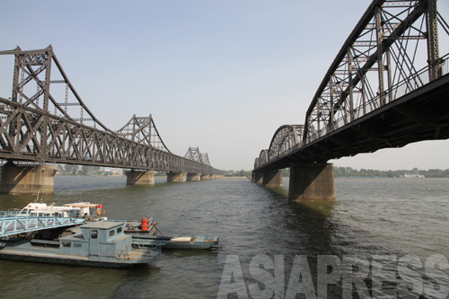 左が鴨緑江大橋。鉄道と車両が並んで通る仕組みになっている。右の橋は朝鮮戦争のさなかの1950年11月、米軍の爆撃により破壊され、その後使われていない。現在は「鴨緑江断橋」と呼ばれ観光地となっている。2011年5月　アジアプレス取材班撮影 (C)アジアプレス