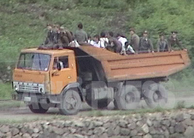 ダンプカーの荷台に軍人と住民が一緒に乗っている。軍人は金を払わないという。（1997年7月両江道恵山市　中国側より石丸次郎撮影）