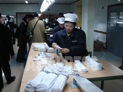 南北経済関係が冷え込む中で、開城工業団地は縮小されながらも運営が続けられている。外貨収入が乏しい北朝鮮にとっては貴重な収入源＝甘い蜜に違いない。写真は工業団地の縫製工場で働く北朝鮮労働者。（2007年2月　アジアプレス取材班撮影）