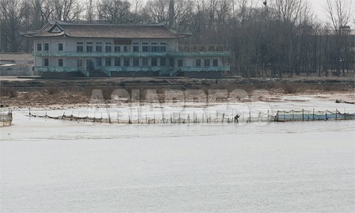 漁師たちが漁網を手入れしている。後ろに見える瓦葺きの建物は「鴨緑江閣」。新義州を訪れる北朝鮮の幹部が会議や宴会を開く所とされる。壁の塗装もはげ、周囲には雑草も生い茂っており、現在も使われているのか定かでない。2012年 3月 南正学（ナム・ジョンハク）撮影（以下全部）