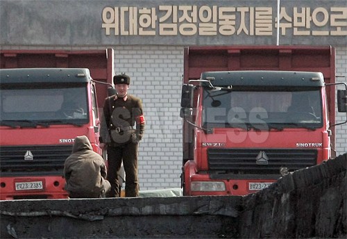 一人の北朝鮮兵士が住民と言葉を交わしている。後ろには「偉大なる金正日同志を首班に」というスローガンが見える。