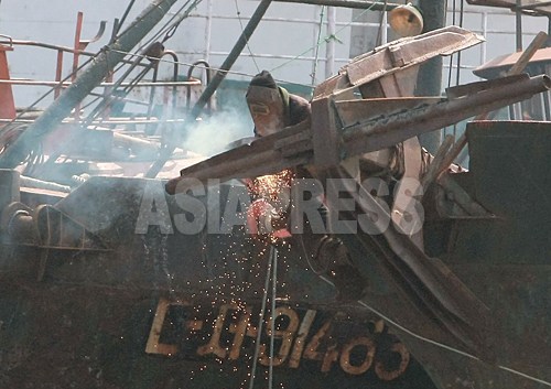 住民が、錆びた船体を溶接修理している。