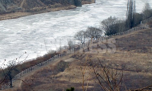 中国側の吉林省和龍市南坪鎮に新たに設置された鉄条網。凍った川が豆満江。対岸が咸鏡北道茂山（ムサン）郡だ。2012年3月南正学（ナム・ジョンハク）撮影