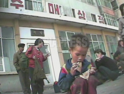 (参考写真)めぐんでもらった食べ物を口に運ぶ男の子。痩せている。黄海北道 沙里院(サリウォン) 2008年9月 シム･ウィチョン撮影