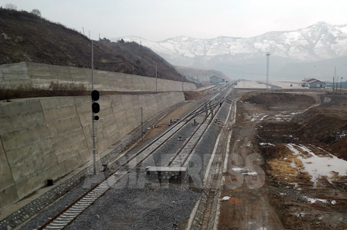 コンクリート製の枕木や、信号の設置も済んでいる。奥に見える広場が駅前にあたる。背後の山並みは北朝鮮。全長40キロ余りの路線は単線で運用される。2012年11月　朴永民（パク･ヨンミン）撮影（アジアプレス）
