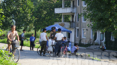 （参考写真）農村で仕入れた穀物を市場に持って行く途中、保安員（警察）の取り締まりに遭遇した夫婦と見られる二人。米を運搬していることを咎められたと思われる。2008年8月平壌市江東（カンドン）郡　撮影：張正吉（チャン・ジョンギル）