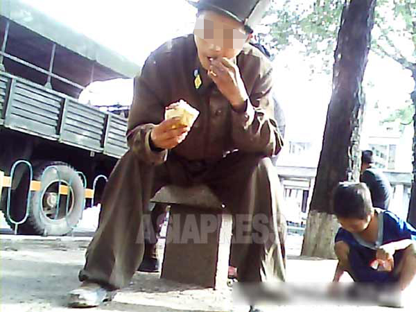 取材協力者が渡したパンを食べる兵士。すぐ脇はコチェビ（ホームレス）の子どもがパンくずを拾っている。2013年8月　北部地域の某都市で撮影
