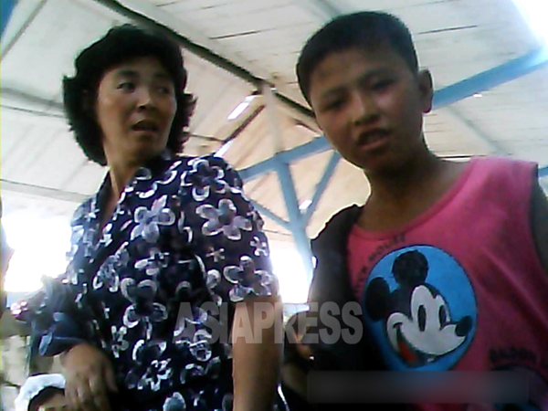 親子連れと思われる２人。少年が着ているTシャツにはミッキーマウスがプリントされている。2013年8月、北朝鮮北部の朝中国境都市、撮影 アジアプレス