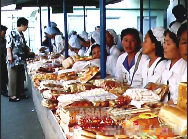 市場でパンや菓子を売る女性たちは雇われではなく幅80センチの売場の主。とても商売熱心な上愛想も良い。（2011年6月平壌市の牡丹（モラン）市場　ク・グァンホ撮影）