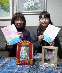 震災で子どもを失った、西宮市のたかいさんちづさん（左）と仙台市の竹澤さおりさんは、絵本「優しいあかりに包まれて」を出版した。亡くなった子どもたちの写真を前に。（撮影：栗原佳子）