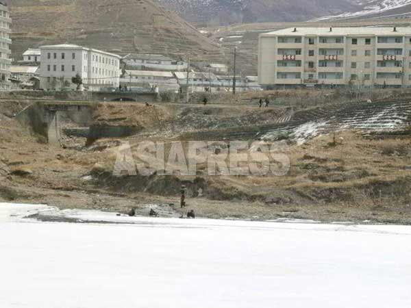 中国長白県から見た恵山市の渭淵(ウィヨン)洞。右奥の５階建てアパートは新しくできたもので、「首領福」「太陽福」「将軍福」の三代世襲を幸いなものと宣伝するスローガンが見える。3月21日に撮影 (アジアプレス)