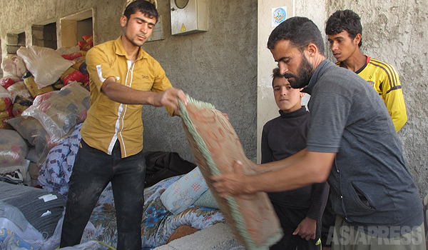 シリアやトルコに暮らすクルド人から集められた支援物資を受け取る避難民。ＹＰＧの開いた脱出路を通ってシリアからトラックで運んでくる。イスラム国の支配地域に囲まれ、輸送は命懸けだ。（９月、イラク・ニナワ県シンジャル山・玉本英子撮影）
