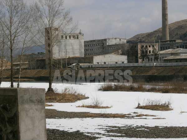 まだ凍ったままの国境の川・鴨緑江を挟んで恵山市内の工場が見える。建物は古び煙突から出る煙も見えない。2014年3月撮影　アジアプレス