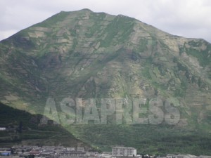 見事に頂上まで開墾された山。木がほとんどなく洪水多発の原因になっている。住民が山肌を開墾する理由は貧困である。 2010年5月、咸鏡北道茂山郡を中国側から撮影。リ・ジンス　（アジアプレス）