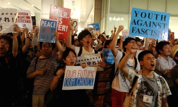 プラカードを持ち、強行採決に抗議する市民ら（大阪駅前にて7月撮影　矢野宏）