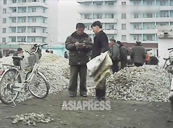 住民が持ってきた砂利の量をチェックする労働動員の責任者。 2013年3月平成市。「ミンドウルレ」撮影（アジアプレス）