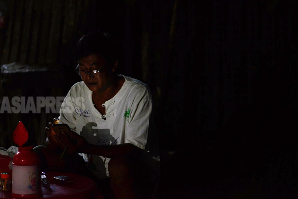 電気の通わない街でも、ビルマでは携帯電話やスマホは必需品。夜が明ける前の喫茶店でスマホの画面に見入る男性。（ラカイン州）撮影 宇田有三