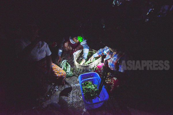 夜明け前の市場、懐中電灯の光で野菜の品定めをし、お金のやりとりをする。（ラカイン州）撮影 宇田有三