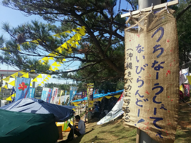 ゲート前のテントに掲げられた「むしろ旗」。5月の県民大会で、翁長知事がスピーチを締めくくったのが、「うちなーうしぇーてぇないびらんどー！（沖縄をバカにするな）」だった（沖縄県辺野古で11月撮影・栗原佳子）