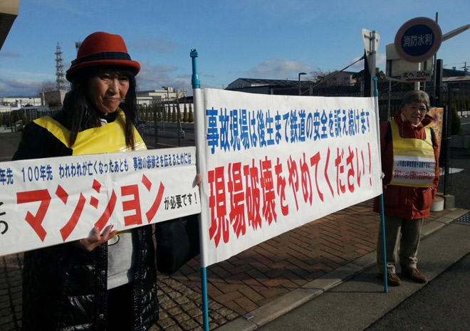 現地には、現状のままでの保存を求める遺族らが「事故現場で破壊をやめて下さい」という横断幕を掲げ、無言の抗議を行っていた。（1月尼崎市で撮影：矢野宏／新聞うずみ火）