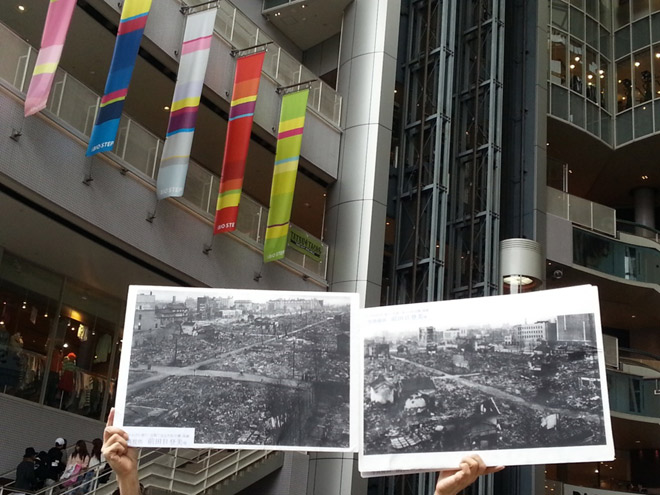 当時の写真とともに空襲の足跡を辿る『ピースウォーク 大阪大空襲を知る』が3月13日開催された。かつて国民学校が建っていたというビッグステップ。空襲後、学校の屋上から撮影された写真を掲げて（矢野宏）