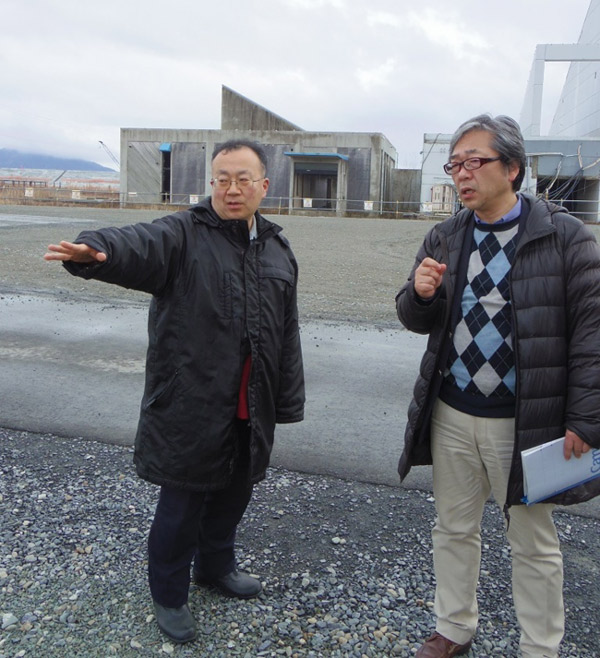 陸前高田市出身のジャーナリスト、佐藤竜一さん（左）の案内で市街地を歩く。(うずみ火)