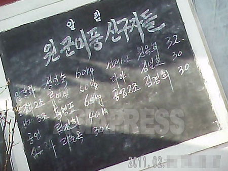 平壌市郊外の公設市場の入り口に設置された黒板。「援軍美風の先駆者たち」と題し、軍糧米を多く納めた商人を称賛している。2011年2月、撮影金東哲（アジアプレス）