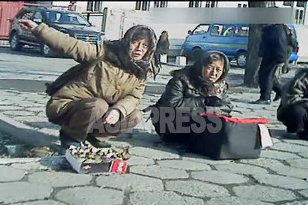 (参考写真)新義州駅前の路上で物売りをする女性。配給のない庶民にもインフレなど制裁の影響必至だと思われるが。2012年11月(アジアプレス)
