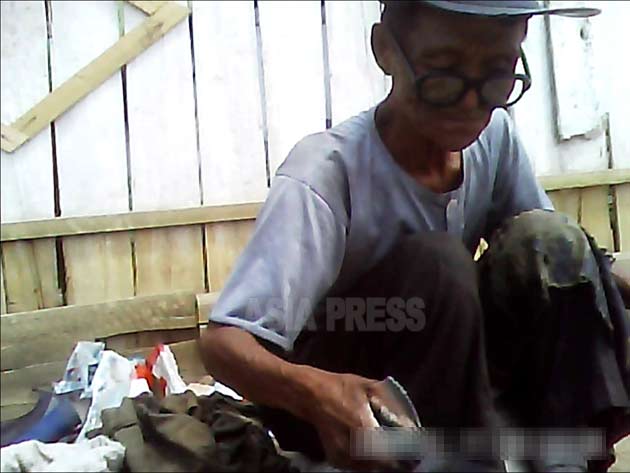 どれだけの収入になるのだろうか? 黙々と修理作業をする老人。2013年6月北部地域で撮影(アジアプレス)。