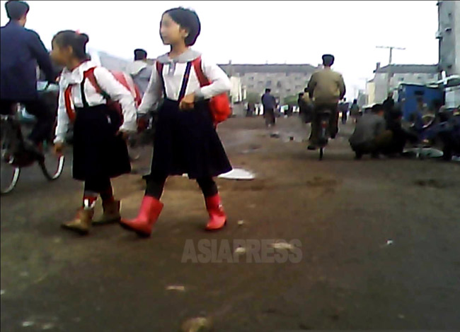 登校する女子小学生。制服はかつては無償だったが、現在はほとんど有償支給。未舗装道が多くぬかるみやすいので長靴は必需品だ。2013年9月、平安南道平城(ピョンソン)市にて撮影アジアプレス