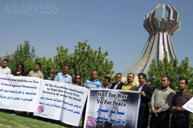 ハラブジャ虐殺記念館のモニュメントの前に立つ参加者たち。「戦争ではなく、平和を」の横断幕を持ち、訴えた。（ヒクメット・ファイード氏提供）