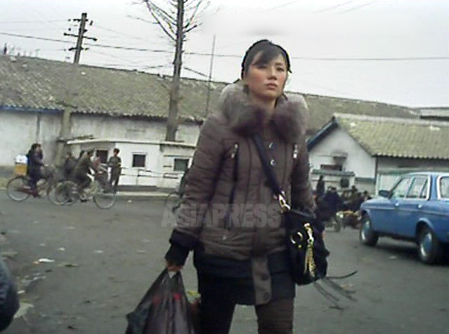 洒落たコートに飾り付きのカバン。髪型も洗練されているように見える。中国の大都市を歩いていそうないで立ちだ。2013年3月平安南道平城(ピョンソン)市にて撮影アジアプレス 