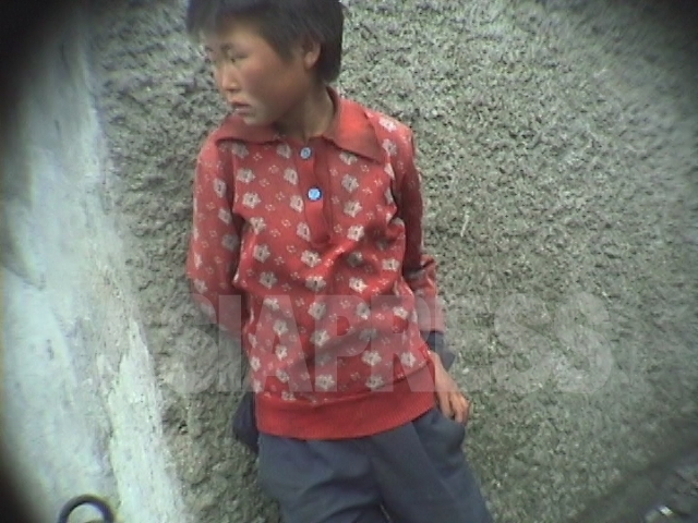 映像を見ると、この少女は行く当てがないのか、物乞いするでもなくじっとしている。見ていても危なっかしく映った。細い首が痛々しい。1998年10月江原道元山(ウォンサン)市にて撮影アン・チョル(アジアプレス) 
