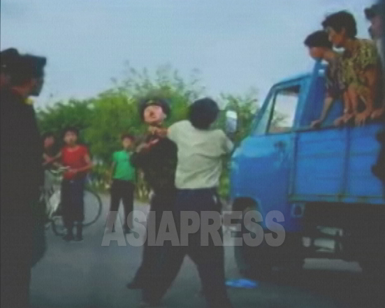 荷台に人を乗せて運ぶ「乗合トラック」に酔った若い警官が因縁をつけた。怒った運転手が車から降りて警官に殴りかかった。荷台の乗客たちも運転手を応援する。2006年8月平壌市郊外で撮影(アジアプレス) 