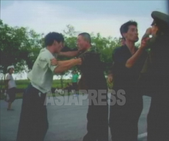 警官の頭突きや蹴りにひるまず運転手もパンチ振るう。周囲にいた人たちを巻き込んで現場は騒動になった。2006年8月平壌市郊外で撮影(アジアプレス) 