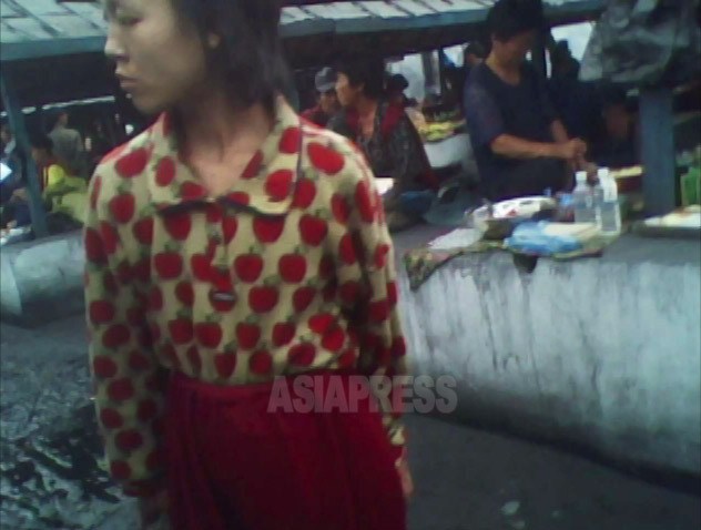 汚れた赤いリンゴのシャツにトレパン姿の少女が市場をぐるぐる徘徊していた。視線はずっと露店の食べ物に向けられていた。2010年6月平安南道にてキム・ドンチョル撮影（アジアプレス） 